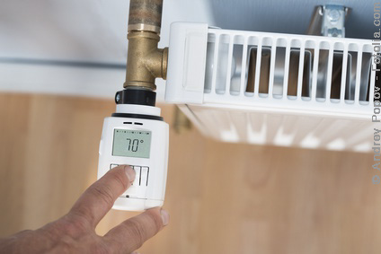 High Angle View Of Person's Hand Adjusting Temperature On Thermostat